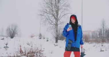 Yavaş çekim bir kayak pisti üzerinde sürüş sırasında bir smartphone kullanarak bir snowboarder