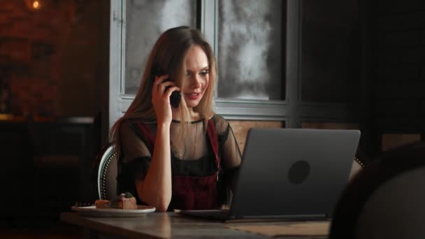 オフィスでラップトップのテーブルの上の白い携帯電話を持つ女性の手. — ストック動画