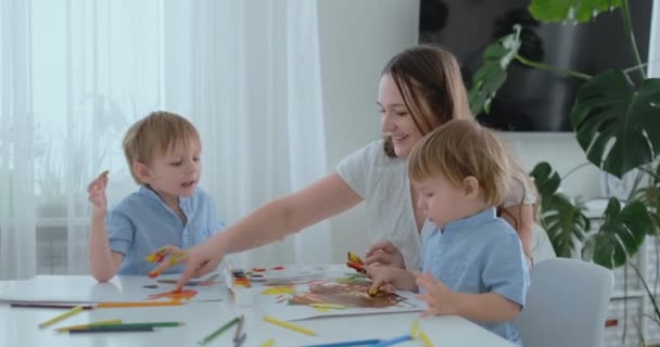 Mamá ayuda a sus hijos a desarrollar habilidades creativas y se compromete con ellos para crear pinturas de dibujo con la ayuda de los dedos. Desarrollo infantil. Familia creativa. Mamá cariñosa — Vídeo de stock