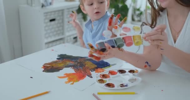 Deux enfants de garçons et de mères sont engagés dans le développement créatif en faisant leurs devoirs en doigtant sur papier. Le développement des sensations tactiles et des petites mathématiques . — Video