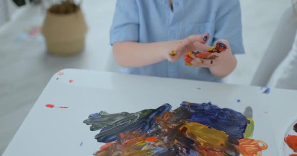 Niños de cerca dibujan sus dedos sobre papel usando pinturas — Vídeo de stock