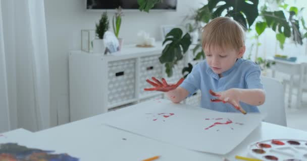 Niño pequeño con las manos pintadas en pinturas de colores listos para las impresiones de mano — Vídeos de Stock