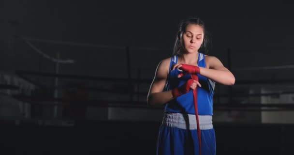 Die schöne Boxerin zieht in Zeitlupe rote Bandagen über ihre Arme. Steadicam-Aufnahme — Stockvideo