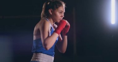 Ağır çekim yan görünümünde arka ışık ile karanlık odada eğitim kadın boksör. steadicam vurdu