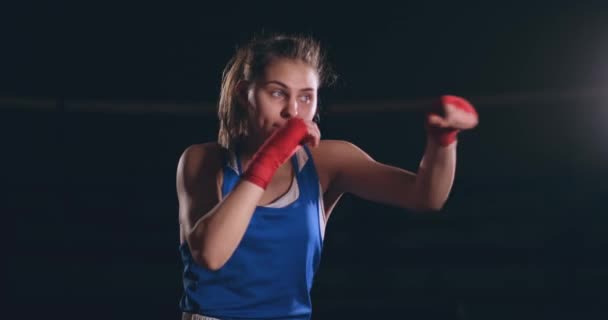 Belle combattante en bandages rouges mène un combat d'ombre tout en faisant de l'exercice dans la salle de gym. Au ralenti. steadicam shot — Video