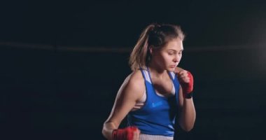 Güzel bir kadın tekniği ve gelecekteki zaferi ise eğitim sert vuruş hızını pratik bir gölge dövüşü yürütmektedir. Koyu spor salonu arka plan. steadicam vurdu