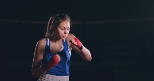 Une belle femme mène un combat d'ombre tout en pratiquant dur pour les victoires futures. Fond sombre de gymnase. steadicam shot — Video