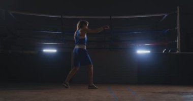 Güzel kadını avcı kırmızı bandaj içinde spor salonunda egzersiz yaparken bir gölge dövüşü yürütmektedir. Ağır çekim. steadicam vurdu