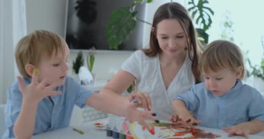 Aile kağıt üzerinde onların parmak boya ile resim eğlenceli. Anne ve iki çocuğu ile kağıt üzerinde parmak boya
