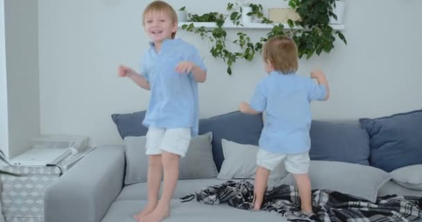 İki küçük çocuğu kanepeye atlama ve having fun — Stok video