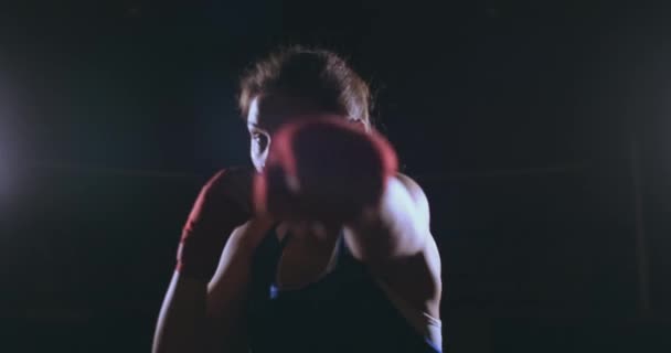 美しいセクシーな女性ボクサーは、動的にバックライトで暗い背景にカメラと前進に直接打ちます。ステディカム ショット — ストック動画