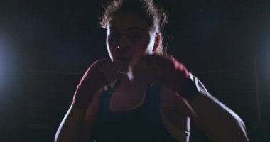 Güzel seksi kadın boksör dinamik olarak bir arka ışık ile karanlık bir arka plan üzerinde doğrudan içine belgili tanımlık fotoğraf makinesi ve hareketli ileri geliyor. Steadicam atış