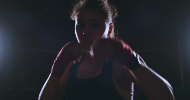 Hermosa mujer sexy boxeador golpea dinámicamente directamente en la cámara y avanzar sobre un fondo oscuro con una retroiluminación. Steadicam tiro — Vídeo de stock