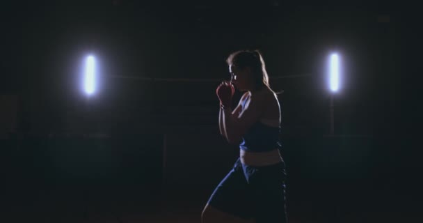 Eine starke athletische Boxerin, die beim Training auf schwarzem Hintergrund boxt. Sportboxkonzept mit Kopierraum. — Stockvideo