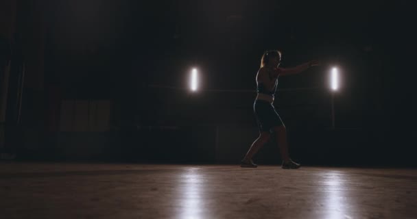 Boxare kvinna i röd bandage på händerna och blå t-shirt bedriver strid med öva hastighet och teknik slår händerna. Kameran rörelse sida Visa. Steadicam skott — Stockvideo