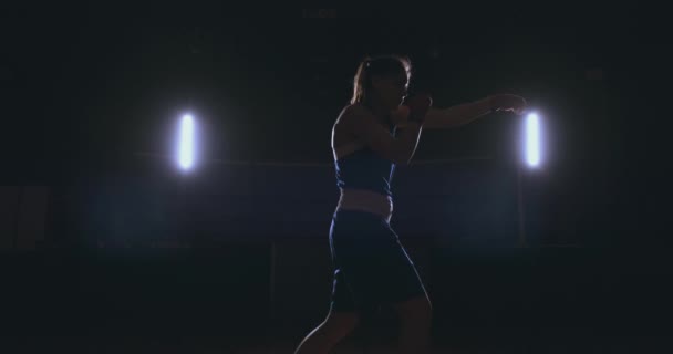 Güzel bir kadın boksör yumruklar karanlık bir odada yapıyor eğitim. Steadicam vurdu. Kendini savunma ve mücadele içinde belgili tanımlık çalmak için hazırlık — Stok video