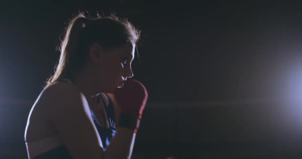 Une belle boxeuse de sport en bandages rouges sur les mains et un t-shirt bleu se bat avec une ombre pratiquant la vitesse et la technique des coups de poing. Caméra côté mouvement Vue. Steadicam shot — Video