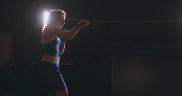 Boksör kadın, el ve mavi t-shirt üzerinde kırmızı bandaj hız pratik ile savaş yürüten ve teknik el saldırır. Kamera hareketi yan görünümü. Steadicam atış — Stok video