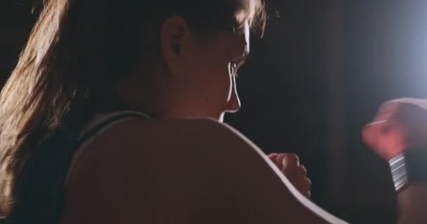 Boxer donna in bende rosse sulle mani e blu t-shirt conduce battaglia con di praticare la velocità e la tecnica colpisce le mani. Movimento telecamera vista laterale. Steadicam shot — Video Stock