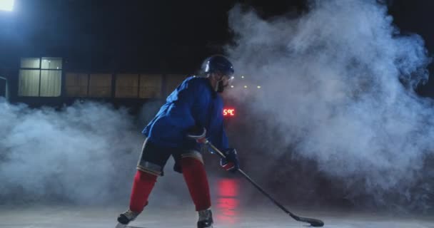 Profesionální hokejista s holí urychluje na ledě a náhle přestane před kamerou dívá přímo do kamery
