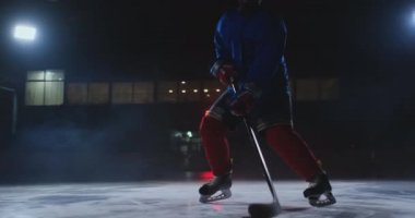 Doğrudan kameraya taşıma ve kamera duman karanlık bir arka plan karşı doğrudan bakarak top sürme erkek hokey oyuncusu buz arenada Pak ile gösterir