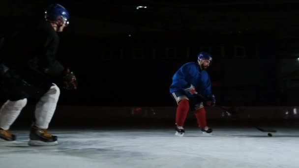 Двое мужчин играют в хоккей на катке. Два хоккеиста сражаются за шайбу. STEADICAM SHOT — стоковое видео