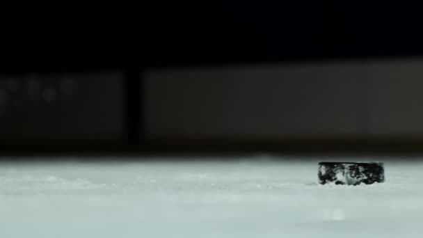 Close-up slowmotion hockeypuck en vliegende sneeuw, hockeyer pikt aan de puck stick — Stockvideo