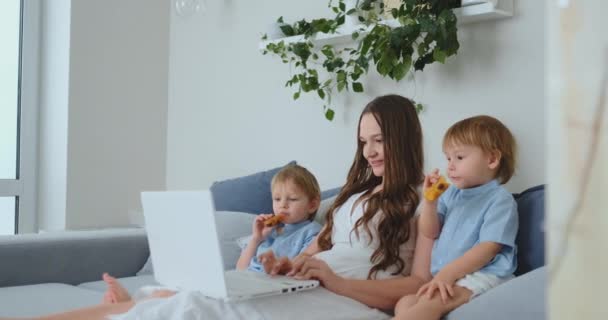 En ung mor och två unga söner göra inköp i onlinebutiken använder en bärbar dator — Stockvideo