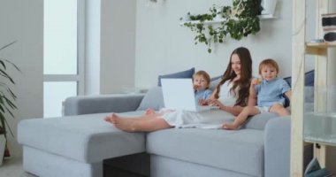 Güzel genç anne ve iki küçük çocuklar çocuklar dizüstü ekran aile fotoğrafları arıyoruz. Ve online alışveriş yapmak