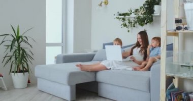 genç bir anne ve iki genç oğlu bir dizüstü bilgisayar kullanarak online mağazada alışveriş yapmak