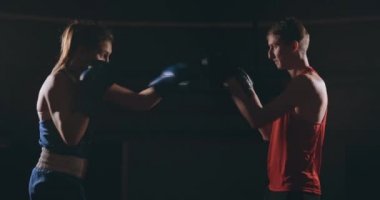 Koçuyla kickboks antrenmanı yapan genç bir kadın..