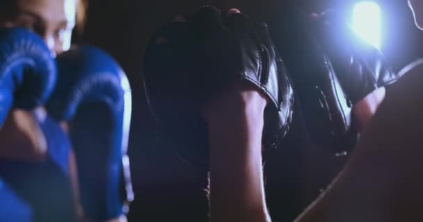 Mittlere Einstellung der schönen Fitness-Boxerin treneruemsya Schlaggeschwindigkeitsfokus Handschuhe mit einem Trainer in einem Boxclub. Zeitlupe — Stockvideo
