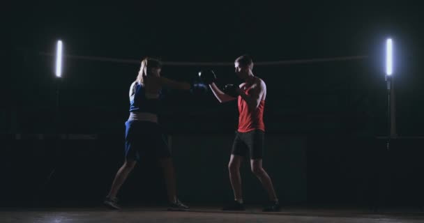 Femme boxer poinçonnant un foyer mitaines avec des gants de boxe dans un gymnase fumé — Video