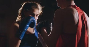 Koçuyla kickboks antrenmanı yapan genç bir kadın..