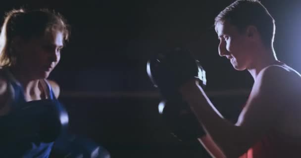 Femme boxer poinçonnant un foyer mitaines avec des gants de boxe dans un gymnase fumé 