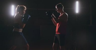 Koçuyla kickboks antrenmanı yapan genç bir kadın..