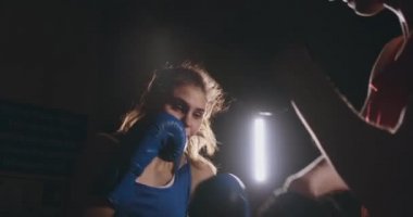 Kadın boksör dumanlı bir spor salonunda boks eldivenli bir odak eldiveni Delme