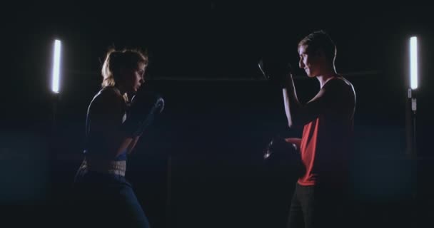 Female boxer punching a focus mitts with boxing gloves in a smoky gym — Stock Video