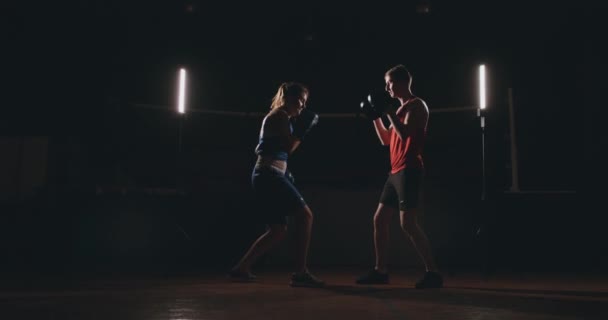 Femme boxer poinçonnant un foyer mitaines avec des gants de boxe dans un gymnase fumé — Video