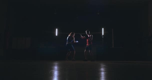 Кикбоксерша-спортсменка тренер по кикбоксингу тренирует женщин-друзей по фитнесу боксируя перчатки для фокуса наслаждаясь интенсивной тренировкой вместе в тренажерном зале вблизи — стоковое видео