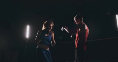 Kadın boksör dumanlı bir spor salonunda boks eldivenli bir odak eldiveni Delme