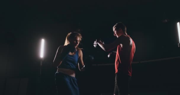 Femme boxer poinçonnant un foyer mitaines avec des gants de boxe dans un gymnase fumé — Video