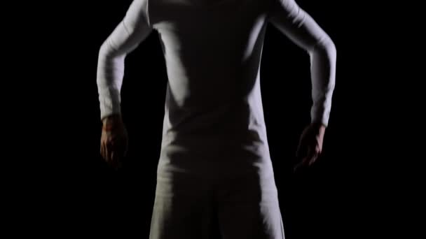 En man i vitt gör akrobatik på en svart bakgrund i slow motion — Stockvideo
