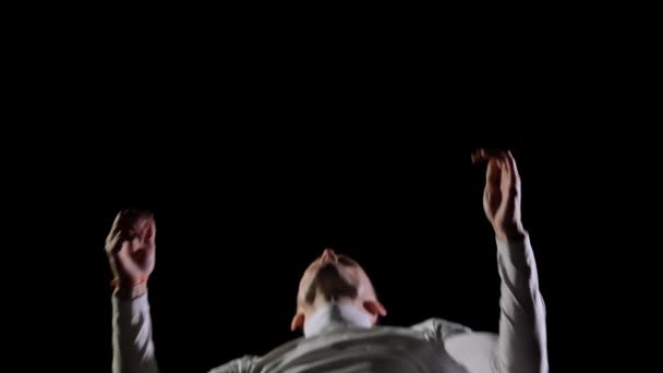 흰색 옷에 슬로우 모션 남자는 곡예 뒤로 플립을 수행 회전과 검은 배경에 점프. 중간 계획. — 비디오