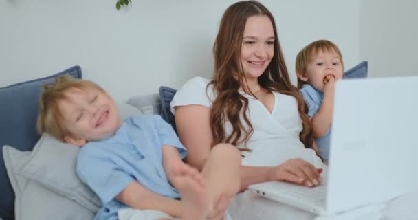 Maman et les enfants rient assis devant l'ordinateur portable et regardent l'écran — Video