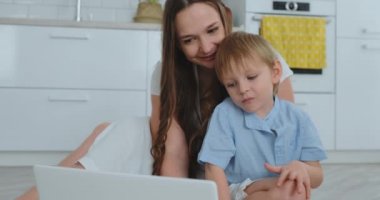 Sevgi dolu anne ve sarılma ve having fun alt katta oturan oynuyor. Eğlenceli ve mutlu bir aile. Belgili tanımlık laptop gördükten sonra oyunu