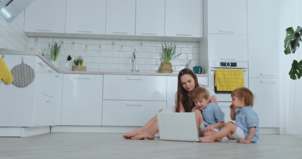 Una joven madre progresista con dos hijos pequeños está hablando con su padre a través de la comunicación por video. La tecnología moderna es una familia joven . — Vídeo de stock