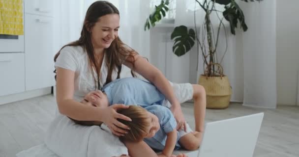 Schöne moderne junge Familie zu Hause auf dem Boden liegend und etwas im Laptop machend — Stockvideo