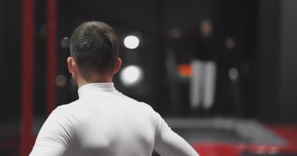 Male gymnast in the trampoline center back watching the performance of tricks rivals. — Stock Video