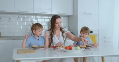 Annesi ile iki küçük kardeş Burger gülmek ve birlikte gülümseme yapmak. Mutfakta mutluluk ailesi